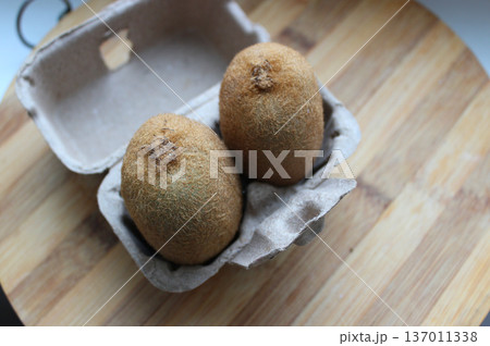 Two whole kiwi fruits in a small cardboard box for two fruits  137011338