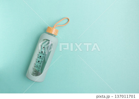 A glass water bottle with time markers on a blue background. A glass water bottle with time markers on a blue background. 137011701