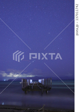 A wrecked pier after a storm, and stars and clouds in the sky. Lightning and thunder over the islands in the Aegean Sea. A perfect photograph for a meteor shower. A wrecked pier after a storm, and stars and clouds in the sky. Lightning and thunder over the islands in the Aegean Sea. A perfect photograph for a meteor shower. 137011742