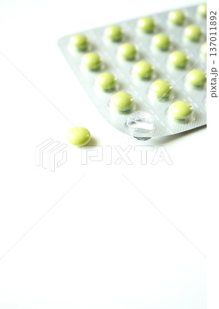 Green pills in a blister pack on white background. Healthcare and medicine, pharmaceutical industry. Green pills in a blister pack on white background. Healthcare and medicine, pharmaceutical industry. 137011892