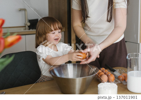 Mother and little daughter baking together in modern kitchen at home, happy family cooking and spending time together Mother and little daughter baking together in modern kitchen at home, happy family cooking and spending time together 137011901