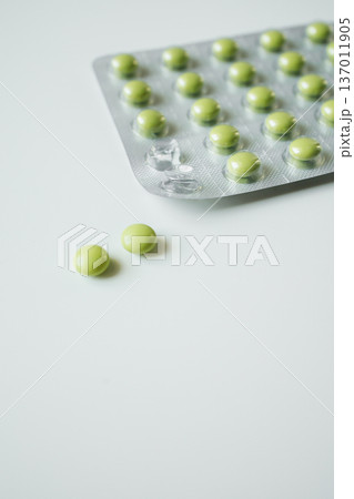 Green pills in a blister pack on white background. Healthcare and medicine, pharmaceutical industry. Green pills in a blister pack on white background. Healthcare and medicine, pharmaceutical industry. 137011905