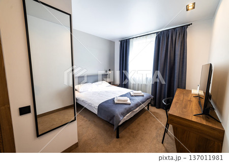 Modern minimalist hotel bedroom interior with double bed workspace and natural daylight 137011981