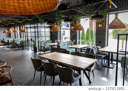 Modern restaurant interior with wooden tables and cozy seating near panoramic windows 137011982