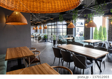 Modern restaurant interior with wooden tables and cozy seating near panoramic windows 137012003