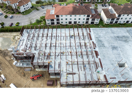 Industrial construction site with workers assembling metal frame building. Development of residential housing in America. Real estate market in the USA Industrial construction site with workers assembling metal frame building. Development of residential housing in America. Real estate market in the USA 137013003