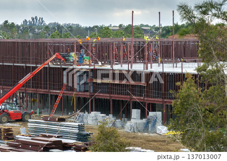 Workers assembling metal frame building at industrial construction site. Housing development in America. Real estate market in the USA 137013007