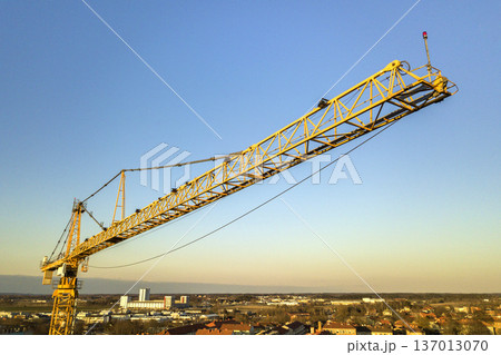 Tower crane on bright blue sky copy space background, city landscape stretching to horizon. Drone aerial photography. 137013070