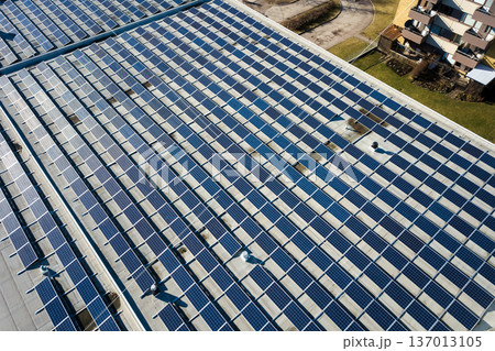 Aerial view of many photo voltaic solar panels mounted of industrial building roof. Aerial view of many photo voltaic solar panels mounted of industrial building roof. 137013105
