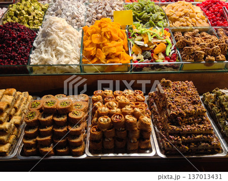 Assorted baklava and dried fruit in market display. Culinary tradition, gastronomy tourism and indulgence concept. Assorted baklava and dried fruit in market display. Culinary tradition, gastronomy tourism and indulgence concept. 137013431