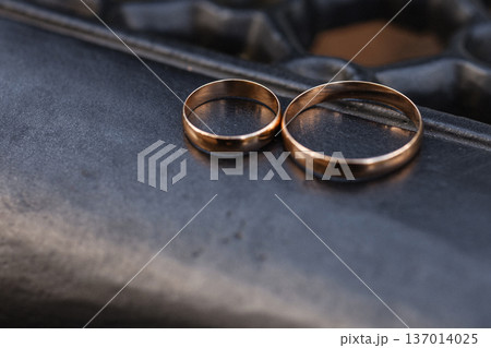 Two gold wedding rings lying on dark metal bench surface close up Two gold wedding rings lying on dark metal bench surface close up 137014025