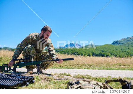 Military Sniper Soldier Preparing Rifle in Open Field Landscape 137014267