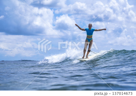 Vigorous Woman Skillfully Maneuvering Through Water Spray On Surfboard 137014673