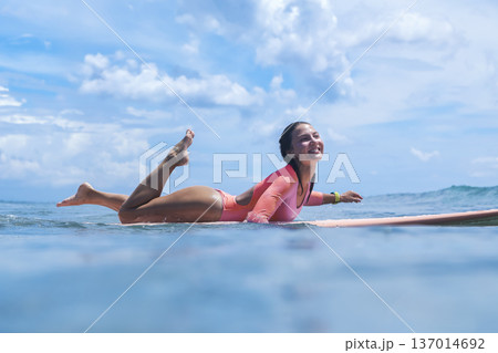 Energetic Young Woman Navigates Surfboard Towards Distant Horizon 137014692