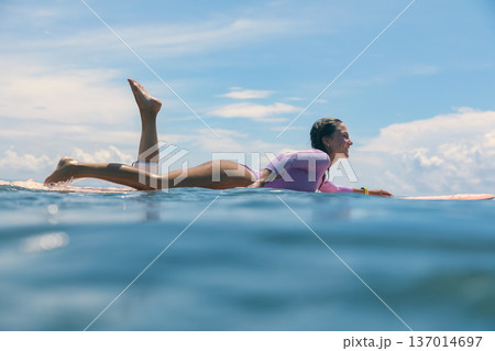 Woman Sitting On Surfboard Amid Breaking Wave Playful Beach Session 137014697