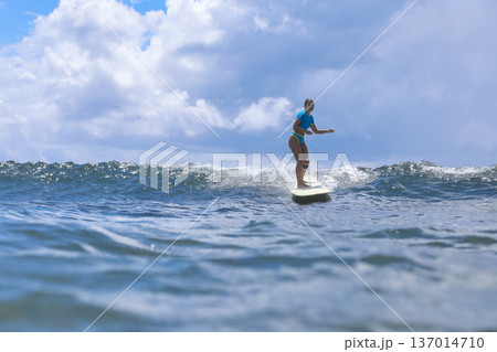 Woman Standing Proudly On Surfboard Amidst Turbulent Cloudy Backdrop 137014710