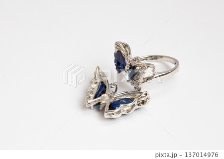 A women's piece of jewelry made of white gold, diamonds, and sapphires in the shape of a butterfly on a white background. 137014976