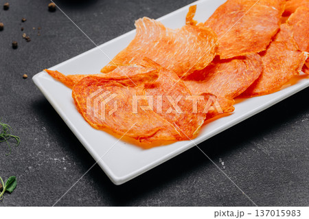 Crispy dried meat chips served on white plate gourmet protein snack closeup Crispy dried meat chips served on white plate gourmet protein snack closeup 137015983