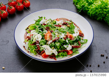 Fresh green salad with tomatoes dried tomatoes and creamy dressing on plate Fresh green salad with tomatoes dried tomatoes and creamy dressing on plate 137015990