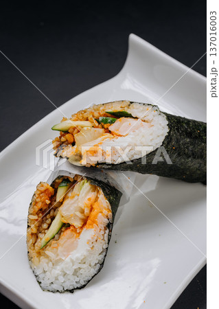 Hand roll sushi with salmon cucumber and rice wrapped in nori on white plate 137016003