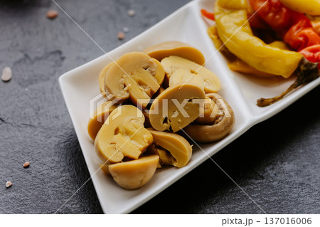 Marinated sliced mushrooms appetizer served on white plate over dark stone background Marinated sliced mushrooms appetizer served on white plate over dark stone background 137016006