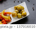 Green olives appetizer served on white plate with Mediterranean antipasti composition 137016010