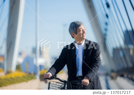 自転車を押して歩く60代男性 137017217