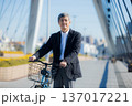 自転車を押して歩く60代男性 137017221