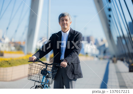 自転車を押して歩く60代男性 137017221