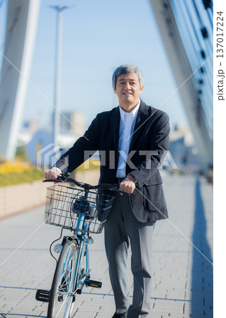 自転車を押して歩く60代男性 137017224