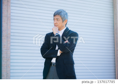社屋建物の前で考える60代男性 137017785