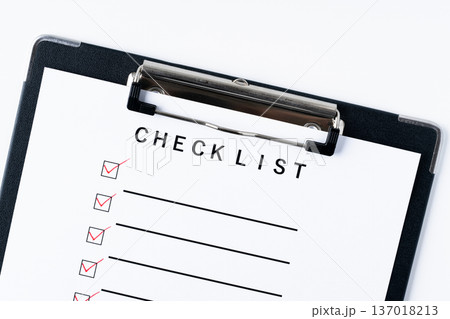赤いレ点を記入したバインダーに挟んだチェックリストの紙のクローズアップ 137018213