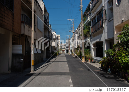 2階、3階建ての建物が両側に並ぶ路地裏の半分が新しく舗装し直された直線の道 137018537