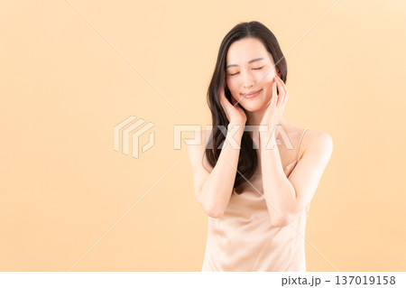 ベージュ背景でスキンケアをする女性のビューティーイメージ ベージュ背景でスキンケアをする女性のビューティーイメージ 137019158