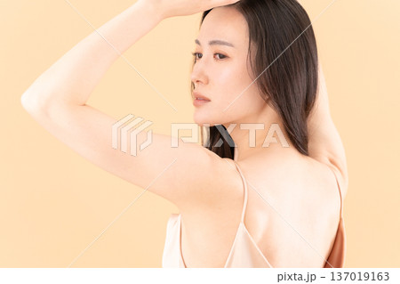 ベージュ背景でスキンケアをする女性のビューティーイメージ 137019163