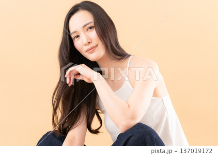 ベージュ背景でスキンケアをする女性のビューティーイメージ ベージュ背景でスキンケアをする女性のビューティーイメージ 137019172