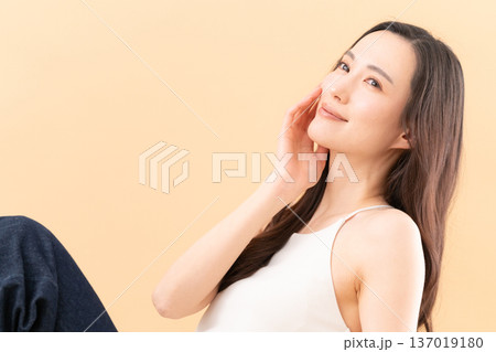 ベージュ背景でスキンケアをする女性のビューティーイメージ ベージュ背景でスキンケアをする女性のビューティーイメージ 137019180