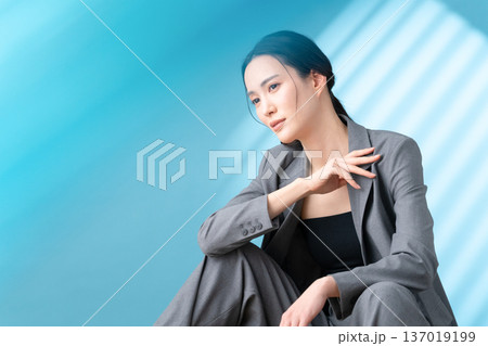 ブルー背景でスキンケアをする女性のビューティーイメージ 137019199