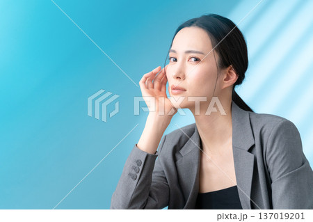 ブルー背景でスキンケアをする女性のビューティーイメージ 137019201