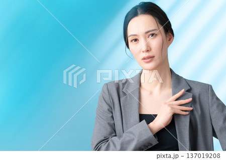 ブルー背景でスキンケアをする女性のビューティーイメージ ブルー背景でスキンケアをする女性のビューティーイメージ 137019208