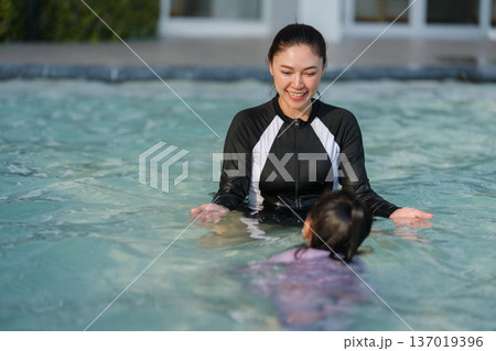 preschool child girl playing and swimming with her mother in pool 137019396