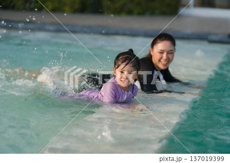 mother with preschool child girl kicking water splashing by legs while practicing swimming in edge of a pool mother with preschool child girl kicking water splashing by legs while practicing swimming in edge of a pool 137019399