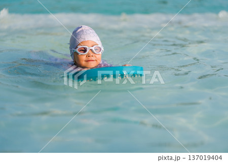 preschool child girl learning to swim with board in swimming pool preschool child girl learning to swim with board in swimming pool 137019404