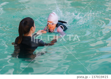 preschool child girl in life jacket learning to swim with mother in swimming pool 137019415