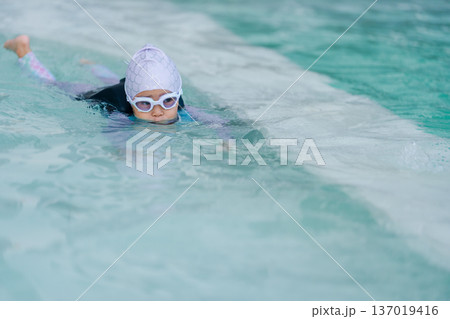 preschool child girl in life jacket playing and swimming in swimming pool 137019416