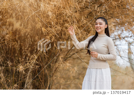 Beautiful woman posing among dry bamboo branches forest in nature. 137019417