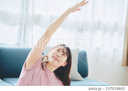 自宅で体をほぐすストレッチをする30代女性の健康習慣 137019602