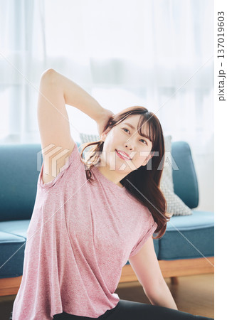 自宅で体をほぐすストレッチをする30代女性の健康習慣 自宅で体をほぐすストレッチをする30代女性の健康習慣 137019603