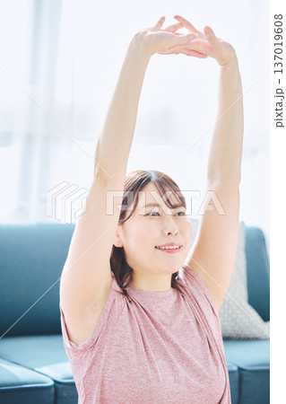 自宅で体をほぐすストレッチをする30代女性の健康習慣 自宅で体をほぐすストレッチをする30代女性の健康習慣 137019608