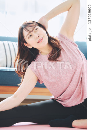 自宅で体をほぐすストレッチをする30代女性の健康習慣 137019609